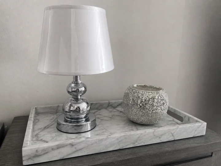 Shiny chrome lamp, glossy faux-marble tray, and glittery candle holder