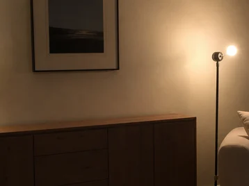 Tiny lamp lost on a wide sideboard and undersized floor lamp with an exposed bulb