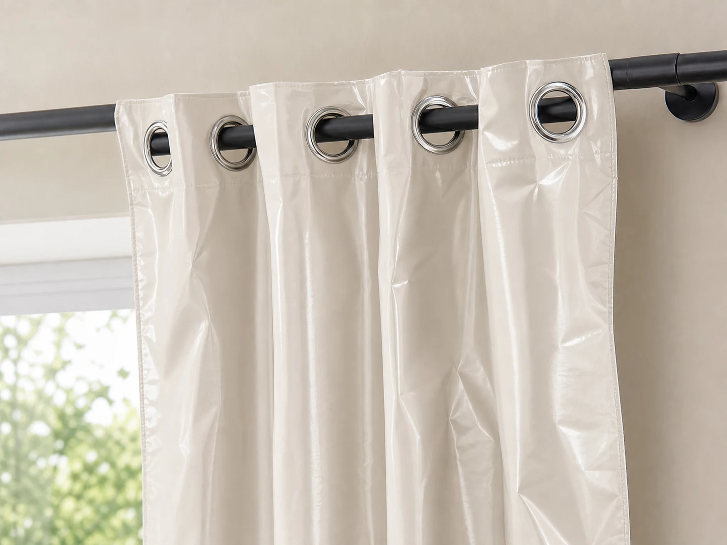 Close view of shiny synthetic curtain with large chrome grommets and packaging wrinkles