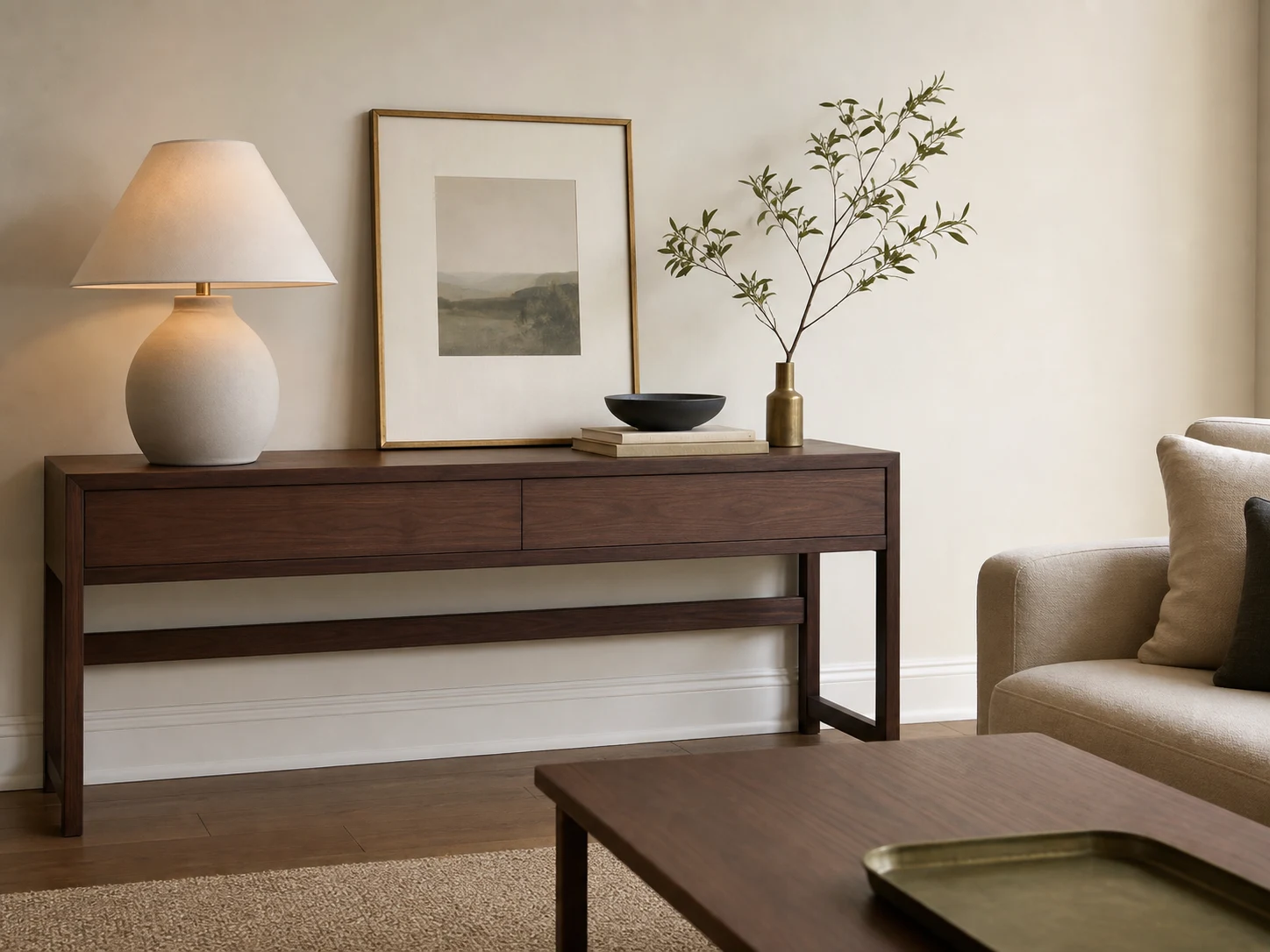 Restrained walnut console with matte lamp, art, books, bowl, and branch